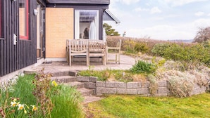 A small house with a brick exterior, a wooden bench, and a stone pathway leading to the entrance. - 6 Person Holiday Home in Borkop (Borkop)