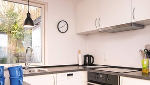 A modern kitchen with white cabinets, a black countertop, a stainless steel range hood, a dishwasher, and an oven. - 6 Person Holiday Home in Borkop (Borkop)
