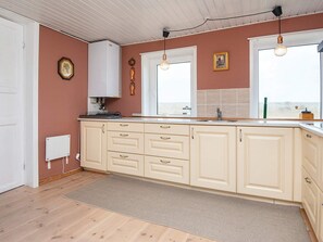 A kitchen with a large island, white cabinets, a window, and a hanging light fixture.