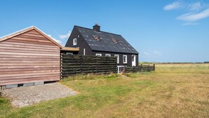 A two-story house with a sloped roof and a wooden fence in front. - 6 Person Holiday Home in Harboore (Harboore)