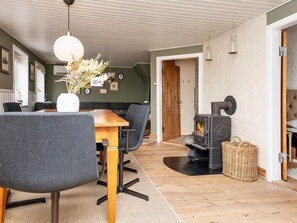 Un intérieur chaleureux avec un coin repas, un poêle à bois et une porte donnant sur une autre pièce.