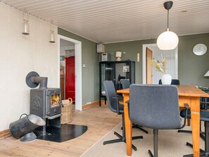 A dining area with a wooden table, grey chairs, a fireplace, and a hanging light fixture.