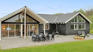 A modern house with a large patio area, outdoor seating, and a visible fireplace. - 4 Star Holiday Home in Tranekaer (Tranekaer)