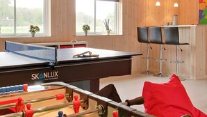 A room with a foosball table, a ping pong table, and a bar area with stools. - 4 Star Holiday Home in Tranekaer (Tranekaer)