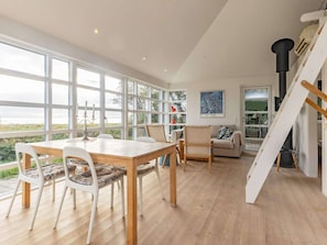 Une pièce spacieuse avec une table à manger en bois, des chaises blanches, un canapé et un escalier.