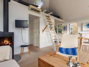 A modern living room with a fireplace, a TV, a staircase, and a dining area. - 4 Star Holiday Home in Martofte (Martofte)
