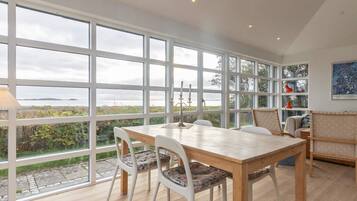 A dining area with a large window, a table, chairs, and a view of the outdoors.