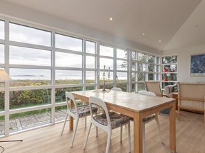 A dining area with a large window, a table, chairs, and a view of the outdoors. - 4 Star Holiday Home in Martofte (Martofte)