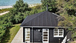 A black house with a sloped roof, a front door, and a window. - 4 Star Holiday Home in Martofte (Martofte)