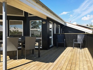 A wooden deck with outdoor furniture, including chairs and a table.