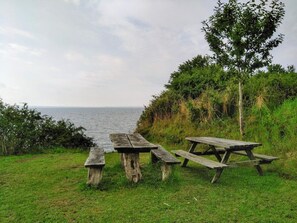 A picnic table set on a grassy area with a view of the sea. - 4 Star Holiday Home in Ronde (Ronde)