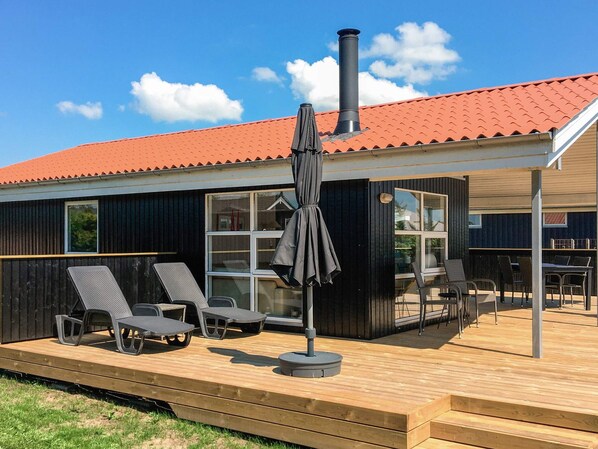 A modern building with a red-tiled roof, a deck with outdoor furniture, and a chimney.