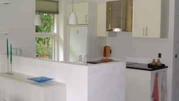 A modern kitchen with white cabinets, a black countertop, and a window with a view of greenery.