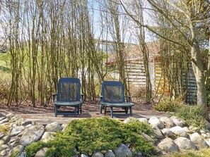 Two outdoor seating areas with chairs and a small garden bed with rocks and shrubs. - 4 Star Holiday Home in Struer (Struer)