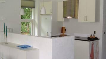 A modern kitchen with white cabinets, a black countertop, and a window with a view of greenery.