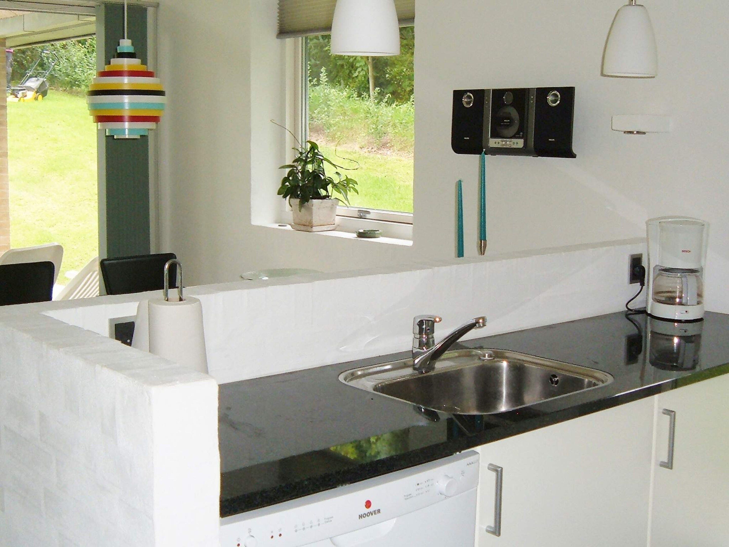 A kitchen with a built-in dishwasher, a sink, and a window with a view of the outdoors.