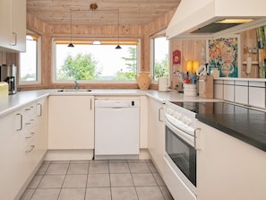 A modern kitchen with a dishwasher, oven, and a large window providing natural light.