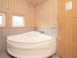 Un bagno con una vasca freestanding, pareti in legno e una finestra.