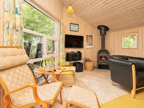 A cozy living room with a fireplace, wooden walls, and large windows. - 8 Person Holiday Home in Saeby (Sæby)