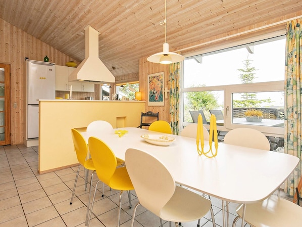 A modern kitchen with a white refrigerator, yellow chairs, and a dining table with yellow napkins.