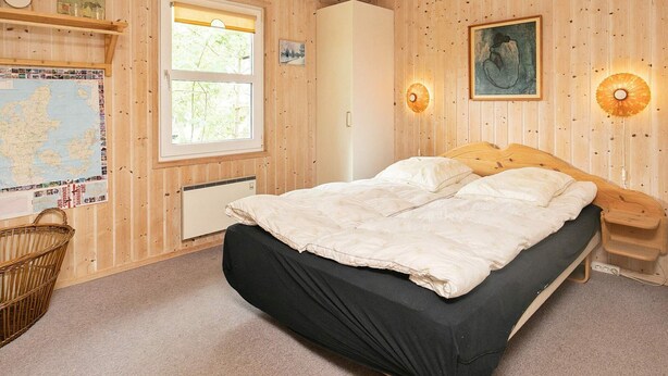Una habitación con paneles de madera, una cama, un mapa, una cesta y un radiador.