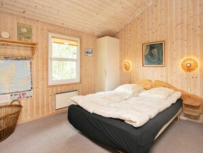 Puupaneelilla verhoiltu huone, jossa on sänky, kartta, kori ja patteri.