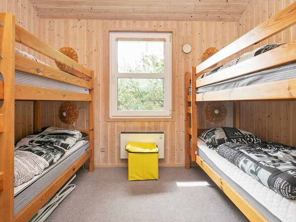 A room with two bunk beds, a window, a radiator, and a small yellow stool. - 8 Person Holiday Home in Saeby (Sæby)