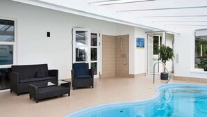 A swimming pool area with a glass-enclosed shower, wicker furniture, and a potted plant. - 8 Person Holiday Home in Ebeltoft-by Traum (Ebeltoft)
