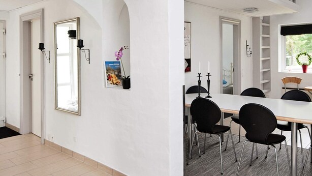 A modern dining area with a white table, black chairs, and a black chandelier. - 8 Person Holiday Home in Ebeltoft-by Traum (Ebeltoft)