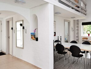 A modern dining area with a white table, black chairs, and a black chandelier.