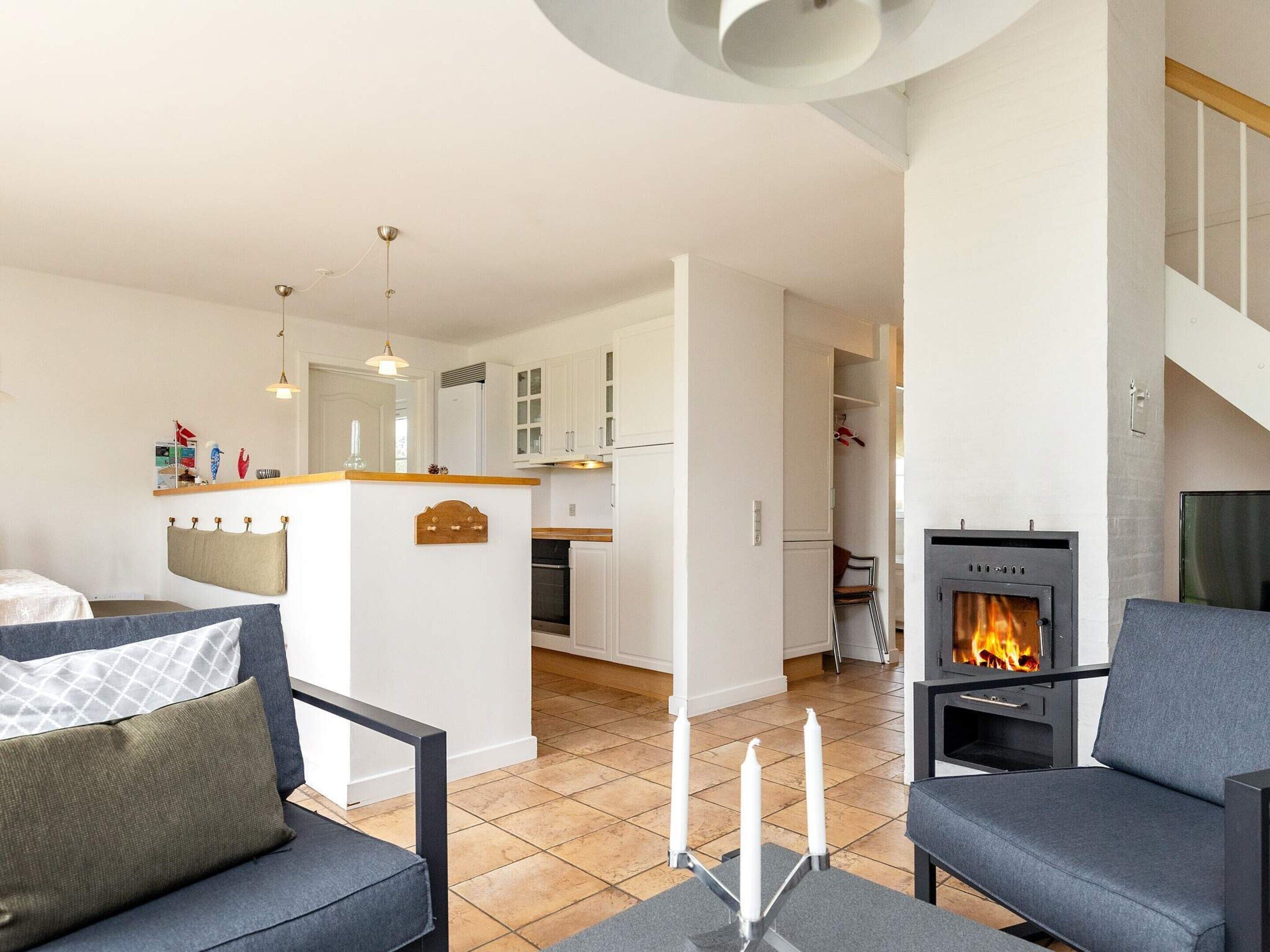 A modern living room with a fireplace, a sofa, and a dining area with white cabinets.