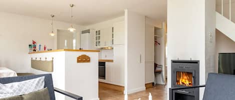 Un salon moderne avec une cheminée, un canapé et un coin repas doté de meubles blancs.