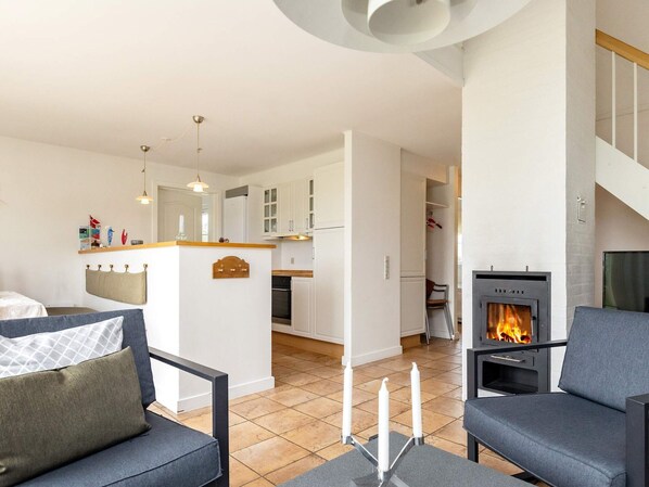 Un salon moderne avec une cheminée, un canapé et un coin repas doté de meubles blancs.