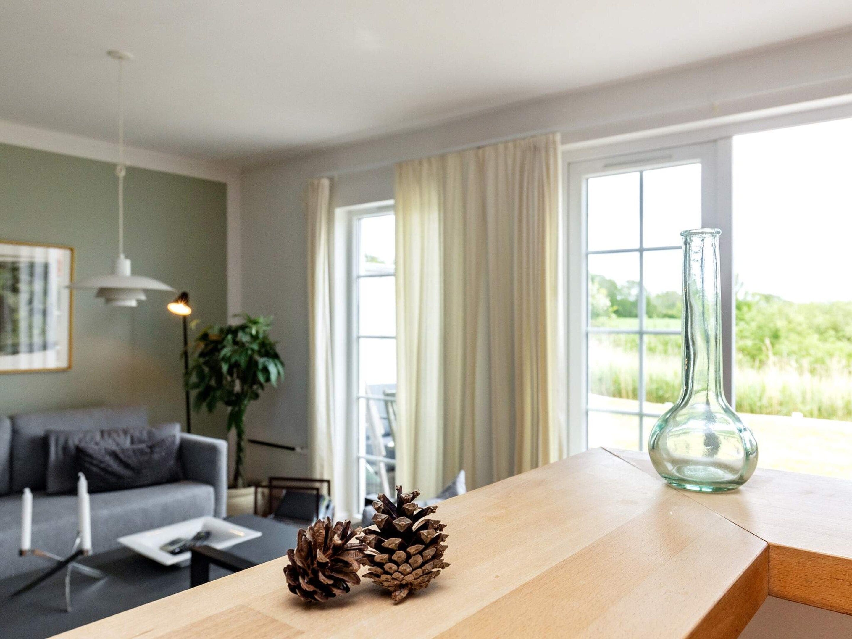 Un salón moderno con una mesa de madera, dos piñas y un florero de vidrio.