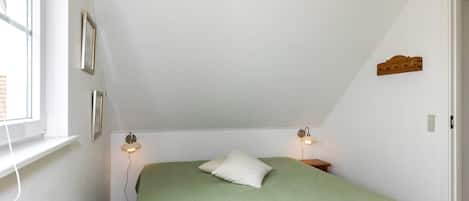 A room with a single bed, a window, and two wall-mounted lamps.