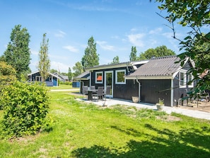 A wooden building with a covered patio area, a flag, and a flagpole. - 4 Person Holiday Home in Hovborg (Hovborg)