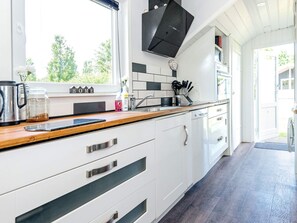 A modern kitchen with white cabinetry, a wooden countertop, and a black range hood. - 4 Person Holiday Home in Hovborg (Hovborg)