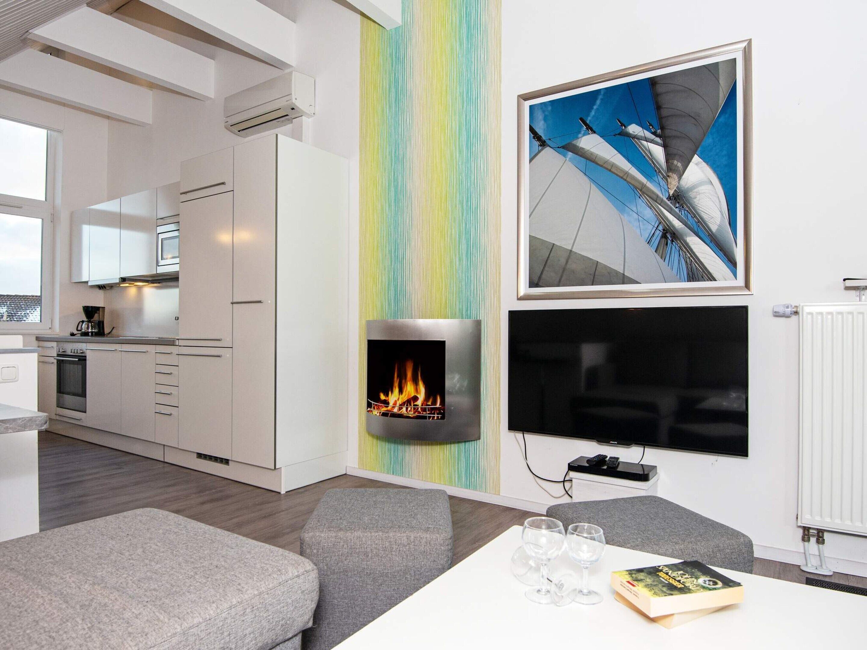 Ein modernes Wohnzimmer mit Kamin, Flachbildfernseher und Essbereich mit Tisch und Stühlen.