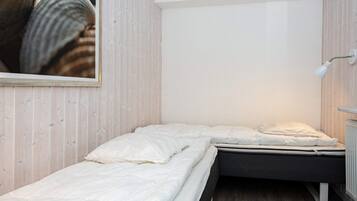 Ein kleines Zimmer mit einem Einzelbett, einer Holzwand und einer weißen Decke.