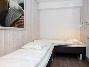 A small, single-bed room with a wooden wall and a white ceiling.