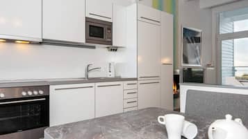 Eine moderne Küche mit weißen Schränken, einer eingebauten Mikrowelle und einem Edelstahlbackofen.