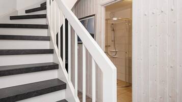 Eine Treppe mit schwarzen Stufen und weißen Geländern, die zu einem Raum mit Dusche führt.