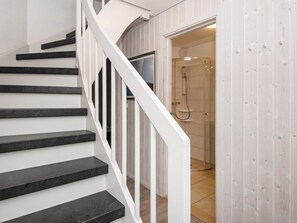 A staircase with black steps and white railings leading to a room with a shower. - Holiday Home in Wendtorf (Wendtorf)
