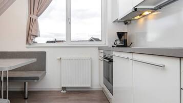 Eine moderne Küche mit Backofen, Kaffeemaschine und einem Fenster mit Vorhängen.