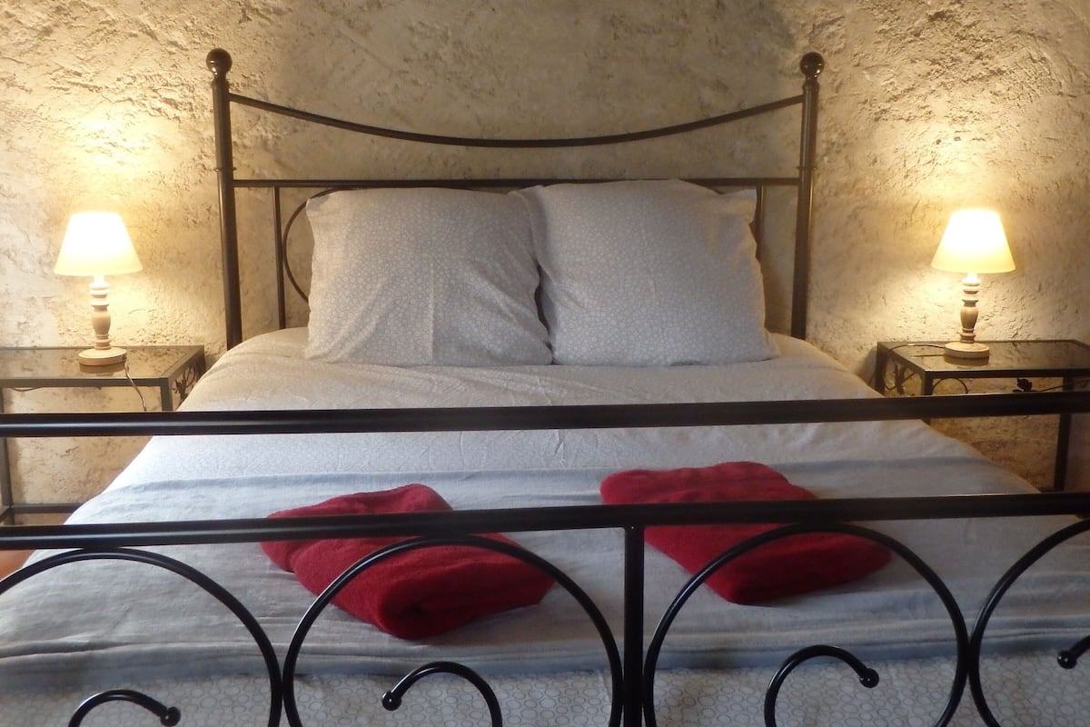 A bed with a metal frame, two bedside tables with lamps, and a textured wall.