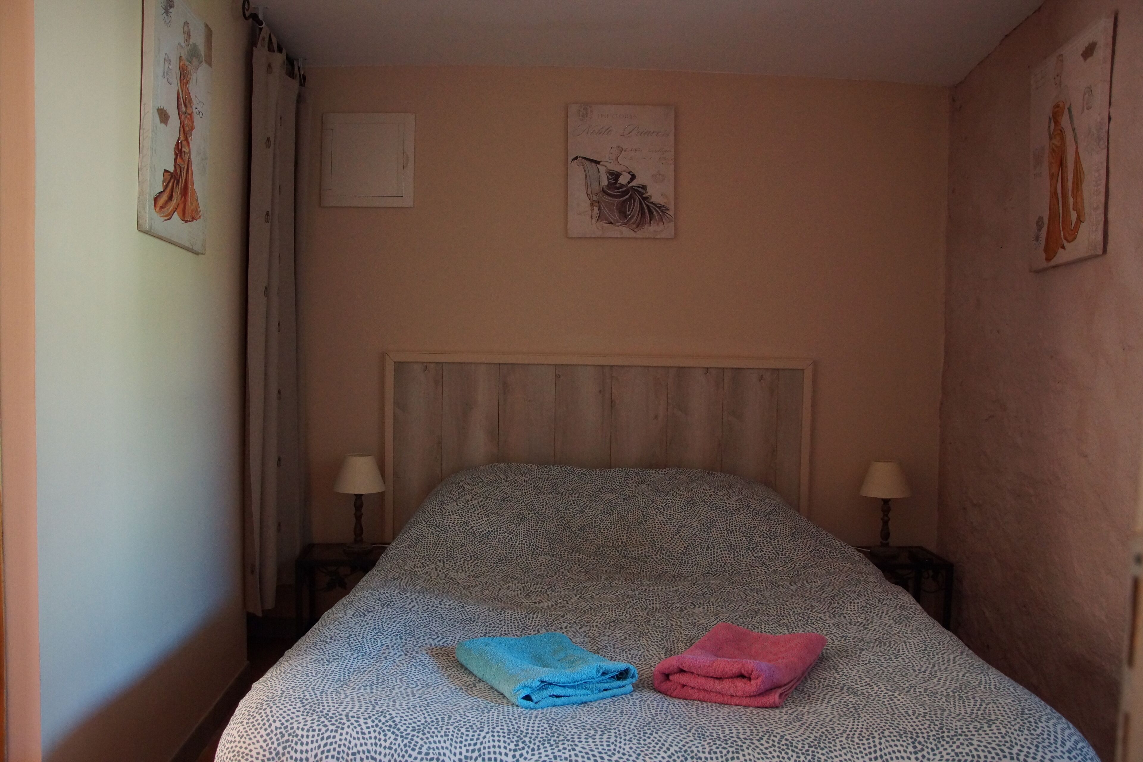 A hotel room with a bed, two nightstands, and wall art.