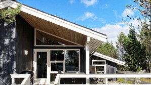 Une maison moderne dotée d’un porche couvert, d’un barbecue et d’une terrasse.