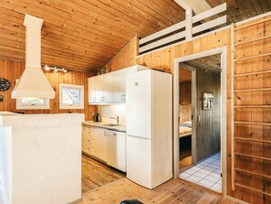 A compact kitchen with white cabinets, a refrigerator, and a wooden ceiling. - 4 Star Holiday Home in Albaek (Aalbaek)