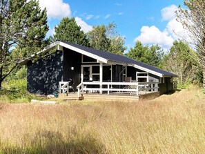 A cabin with a porch, a grill, and a view of the surrounding forest. - 4 Star Holiday Home in Albaek (Aalbaek)