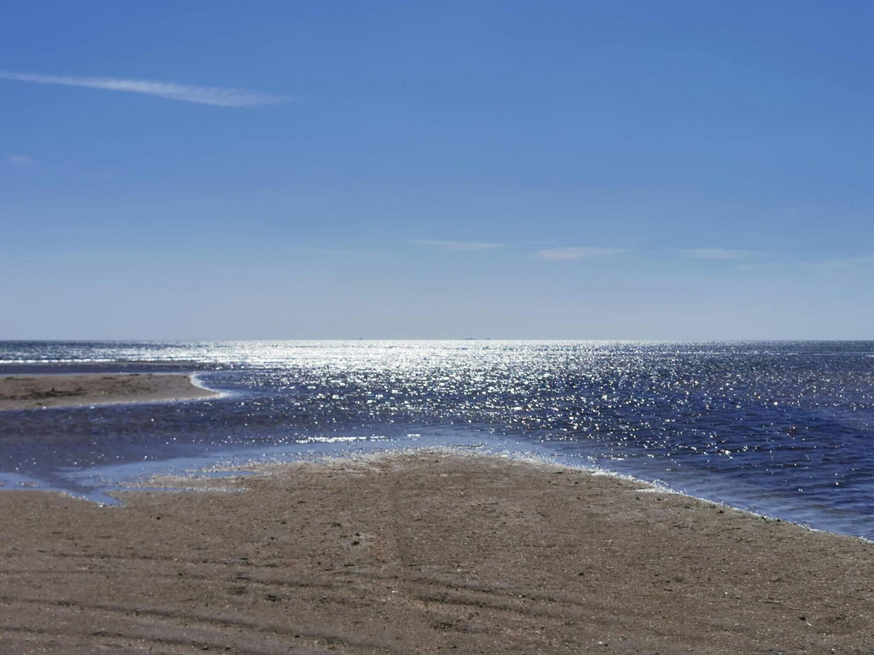 Una playa con cielo despejado y mar tranquilo.
